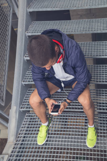 istock Jogger holding smartphone and sitting on stairs 869458776