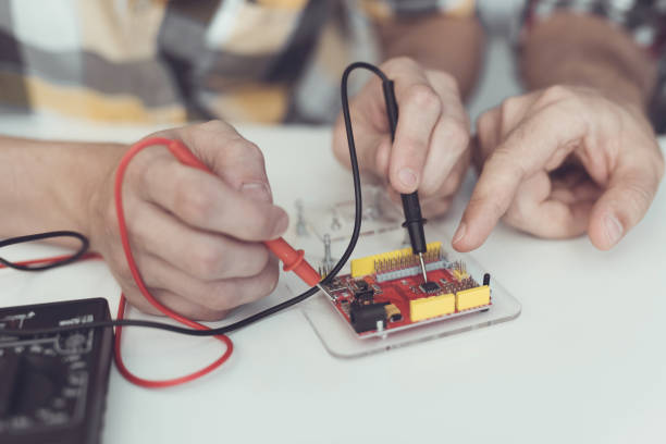 istock The guy and the man examine the board using a multimeter. They measure indicators 869459102