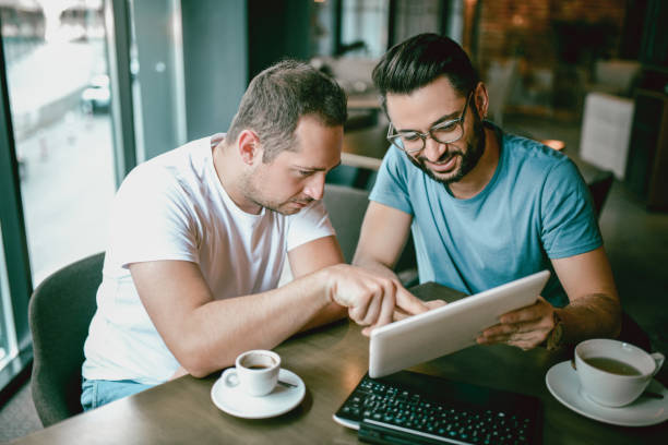 istock Two Serious Male Freelancers Drinking Coffee and Working In Cafe Restaurant 869460072
