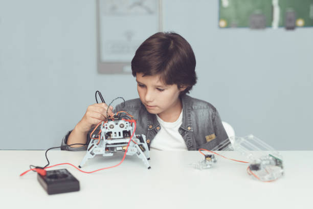 istock The boy creates a robot. He measures his data with a multimeter. The boy observes the measurements 869462394