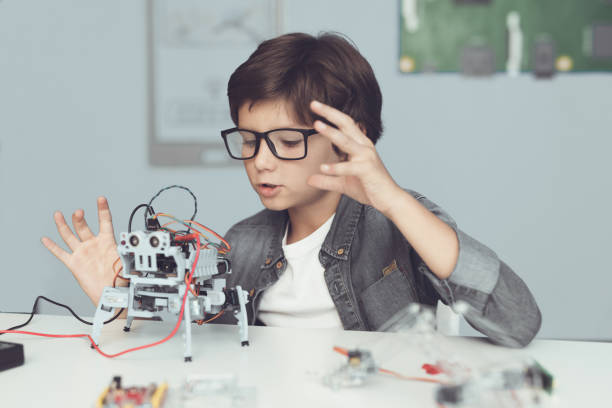 istock A small nerd in glasses is holding a robot. He enthusiastically looks at his creation 869462638