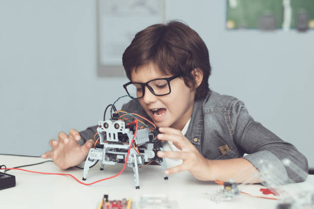 istock A small nerd in glasses is holding a robot. He enthusiastically looks at his creation 869462708