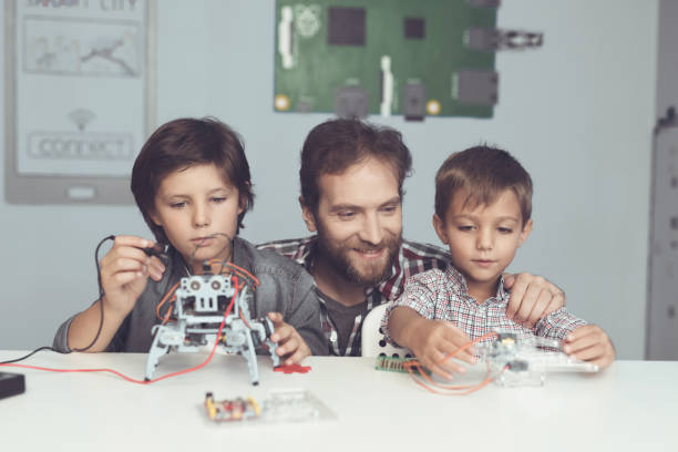 istock A man and two boys construct a robot. The man helps the boys with the assembly 869462882