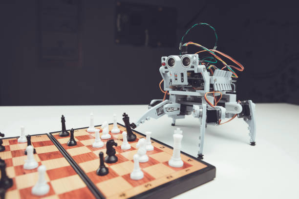 istock Robot close up. A small gray robot is on the table next to the chessboard 869469138