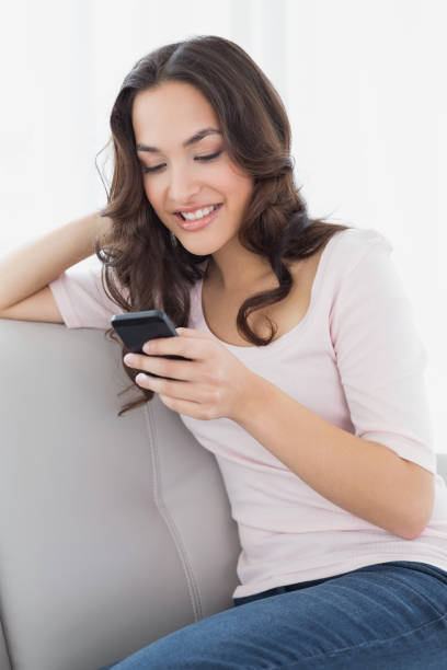 istock Relaxed woman text messaging on sofa at home 869473314