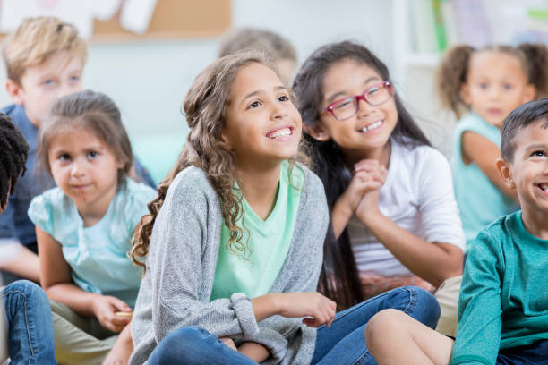 istock Elementary age girl listens during story time with classmates 869476006