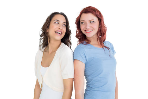 Two cheerful young female friends standing over white background