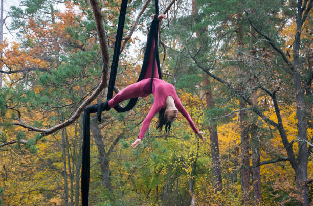 istock Woman dancing with aerial silk on a trees background. 869496326