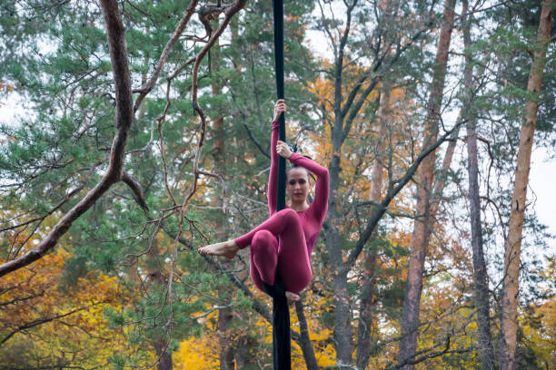 istock Woman dancing with aerial silk on a trees background. 869496528
