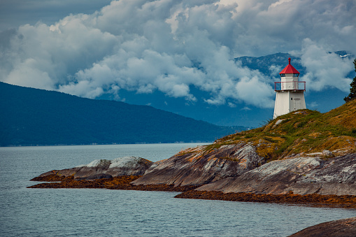 Lighthouse on fjord coast in Norway. Film style colors effect.
