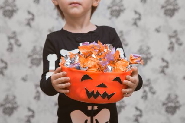 istock Little boy is holding a scary bowl with candies 869503050