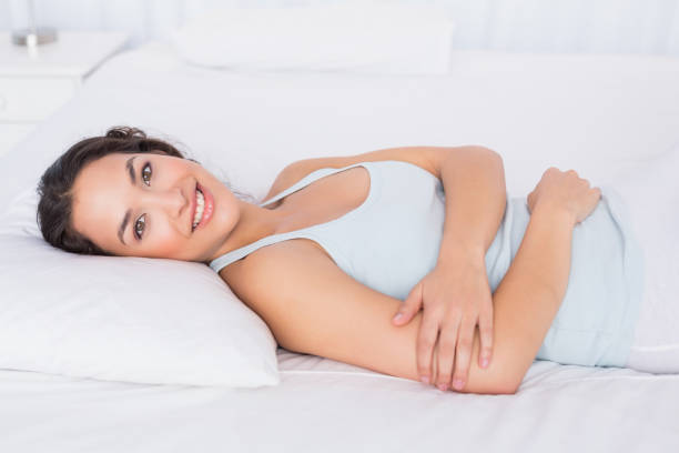 istock Smiling pretty young woman relaxing in bed 869503286