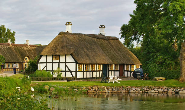 Lyo, Denmark - July 4th, 2012 - Traditional timber-framed thatched Danish farmhouse with pond in the foreground on the island of Lyo stock photo