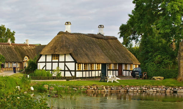 lyo, dinamarca - 4 de julho de 2012 - madeira palha dinamarquês quinta tradicional com lagoa em primeiro plano sobre a ilha de lyo - denmark house cottage rural scene - fotografias e filmes do acervo