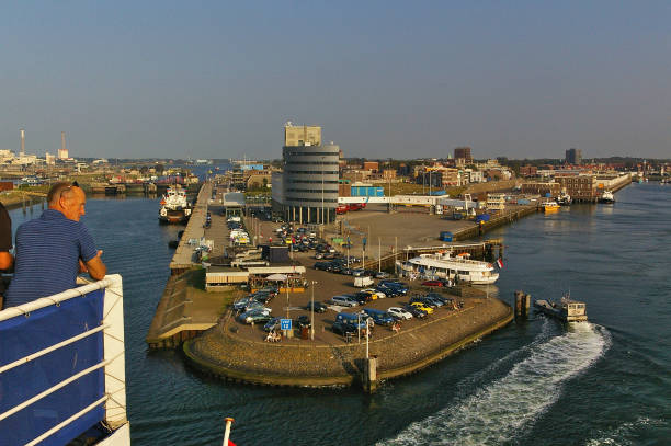 ijmuiden, the netherlands - september 18th, 2014 - ferry terminal in the port of ijmuiden in the evening sun as seen from the upper deck of a departing cruise ship with male passenger in the foreground - ijmuiden imagens e fotografias de stock