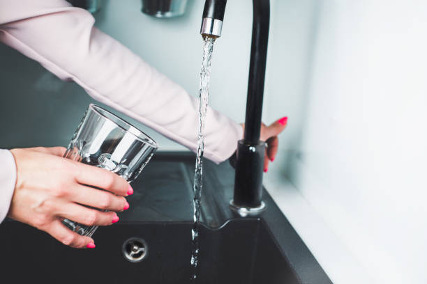 water from the tap, next to the glass. - water human hand stream clean imagens e fotografias de stock