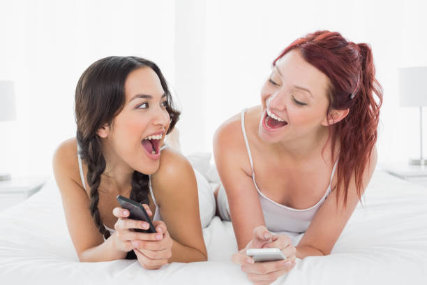 istock Cheerful young female friends text messaging on bed 869510062