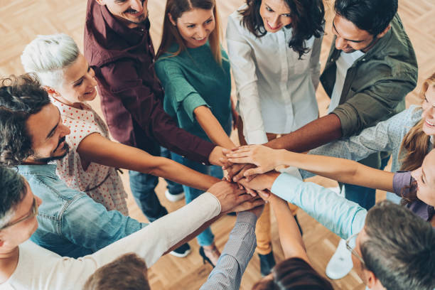 istock Large group of people standing in circle and stacking hands 869511266