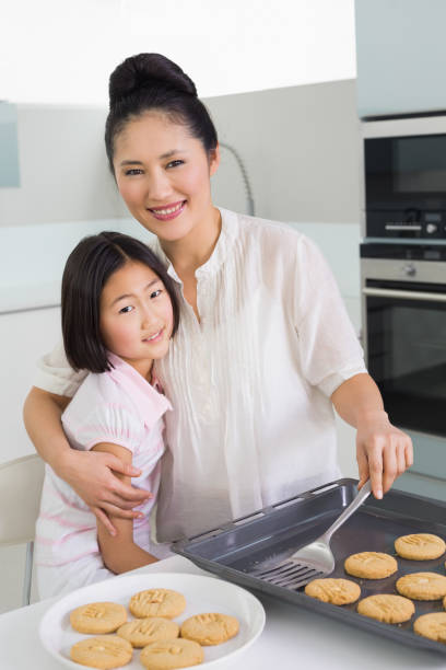 istock Mother hugging daughter while preparing cookies in kitchen 869514278