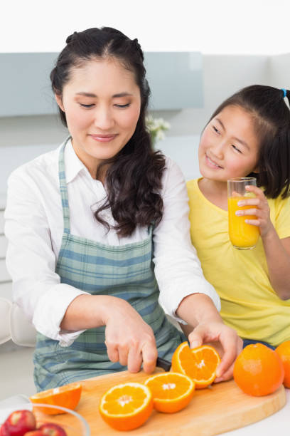 istock Woman with her young daughter cutting fruit in kitchen 869517482