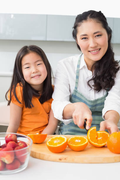 istock Woman with her young daughter cutting fruit in kitchen 869519940