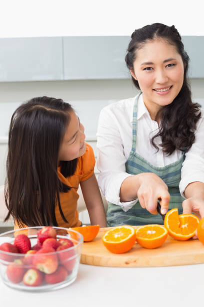 istock Woman with her young daughter cutting fruit in kitchen 869519960