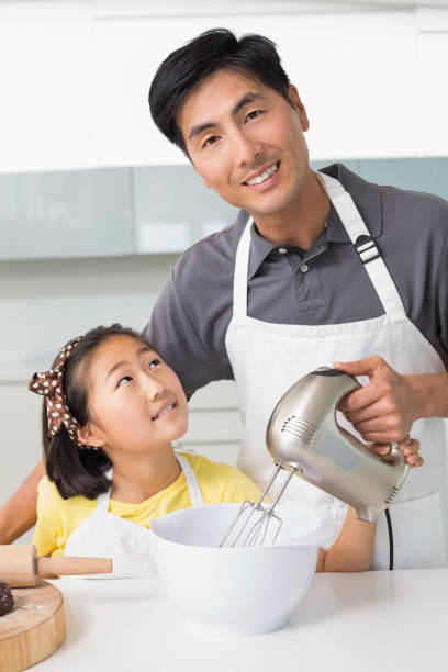 istock Man with his daughter using electric whisk into bowl in kitchen 869520182