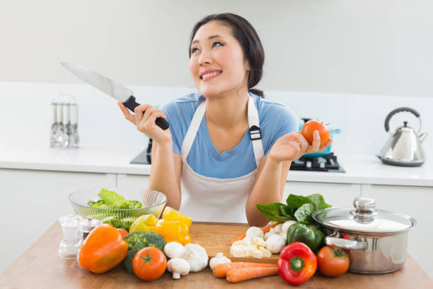 istock Thoughtful woman chopping vegetables in kitchen 869520424
