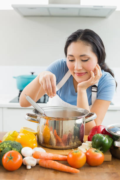 istock Smiling young woman preparing food in kitchen 869521064