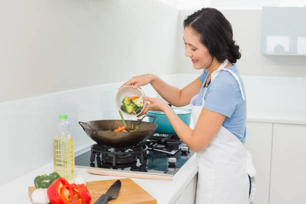 istock Smiling young woman preparing food in kitchen 869523138