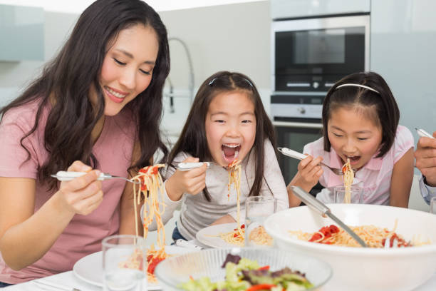 istock Woman with kids enjoying spaghetti lunch in kitchen 869523996