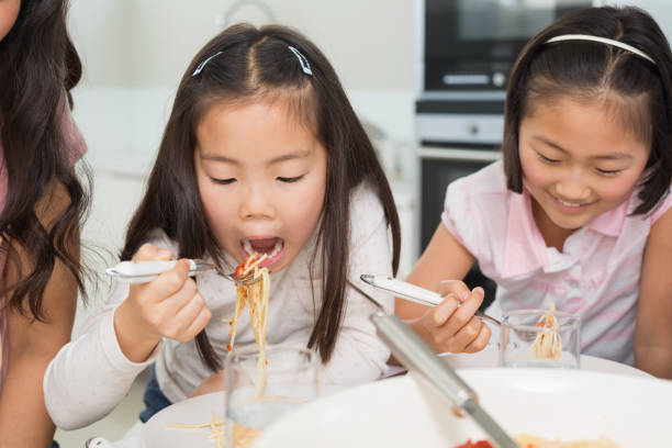 istock Two happy kids enjoying spaghetti lunch in kitchen 869524020
