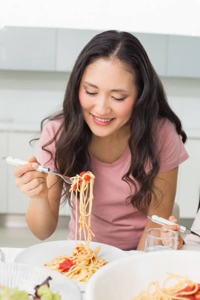 istock Happy young woman enjoying spaghetti lunch 869524052