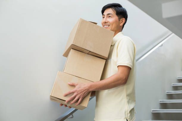 istock Young man carrying boxes against staircase 869524120