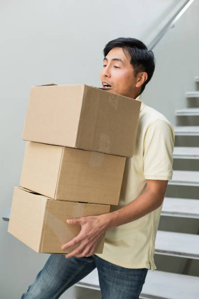 istock Young man carrying boxes against staircase 869524142