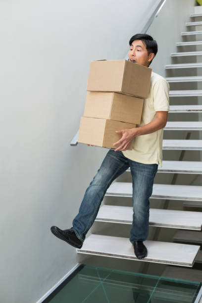 istock Young man carrying boxes against staircase 869524146