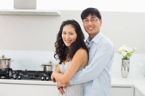 istock Young man embracing woman from behind in kitchen 869530194