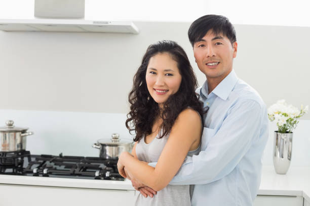 istock Young man embracing woman from behind in kitchen 869530240