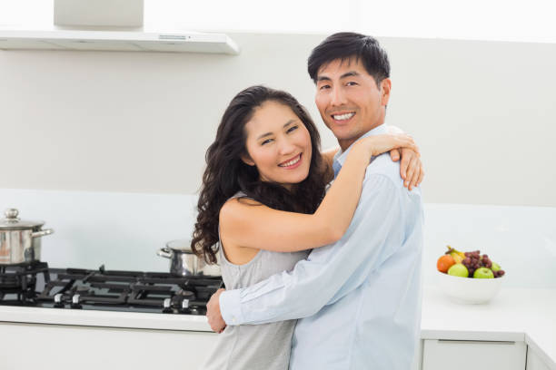 istock Young man embracing woman in kitchen 869530250