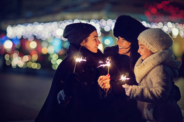 istock Happy mother is hugging her beloved daughters and playing with fireworks 869534634