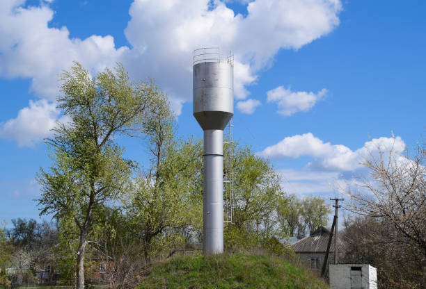 istock Silver Water Tower among green grass and trees 869537926