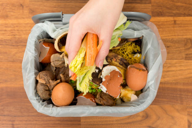 istock Overhead of Hand Placing Food Scraps into a Garbage Bin 869545500