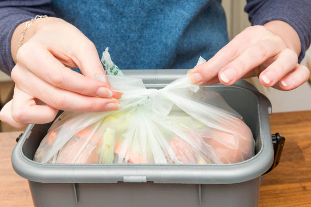 Tying a Plastic Bag Filled with Food Scraps in Waste Bin