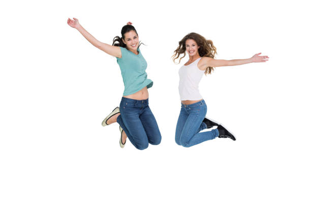 Capture the moment in flight! Our studio portrait freezes the exhilaration of  Asian women mid-jump, their infectious energy and boundless joy filling the frame against a pristine white backdrop.
