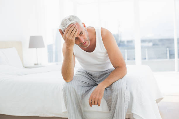 istock Thoughtful mature man sitting in bed 869557940