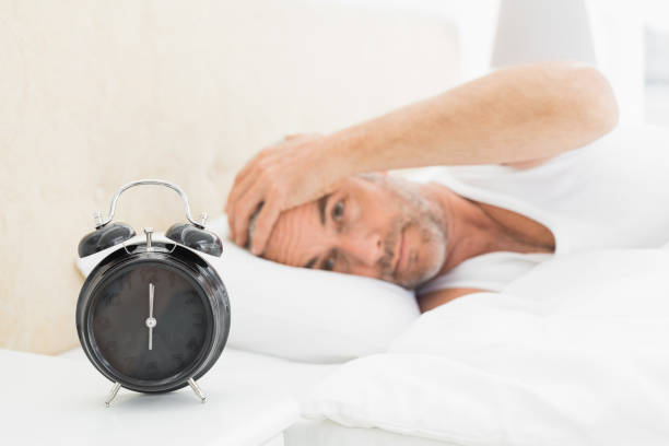 istock Man resting in bed with alarm clock in foreground 869560774