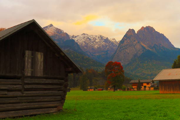 istock Alpine Rustic wooden barn farm, with Zugspitze, Waxenstein and Alpspitze view– dramatic landscape in Bavarian alps, Germany, near Karwendel mountain range - Majestic alpine landscape in autumn – Garmisch, Bavaria, Germany 869561072