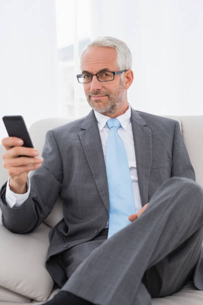istock Elegant mature businessman text messaging at home 869569480