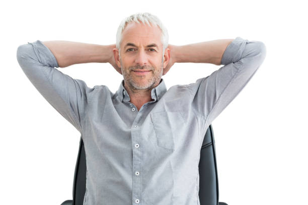 Portrait of a relaxed mature businessman with hands behind head over white background