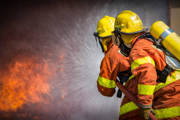 2 firefighters spraying high pressure water to  fire stock photo